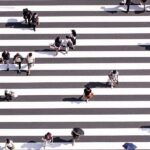 People crossing a busy zebra crossing from many directions, reflecting life choices, paths, and shared human journeys