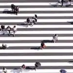 People crossing a busy zebra crossing from many directions, reflecting life choices, paths, and shared human journeys