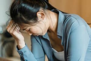 Asian woman distressed with head down, seeking emotional support, relationship counselling Singapore guidance