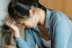 Asian woman distressed with head down, seeking emotional support, relationship counselling Singapore guidance