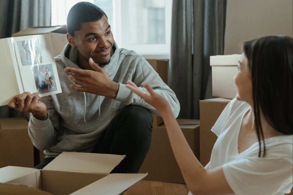 Couple reminiscing with a photo album while unpacking, reflecting on life changes and transitions in Singapore