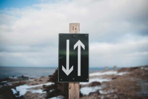 Mountain road sign pointing up and down symbolizing life direction, decisions, and the search for meaning and purpose