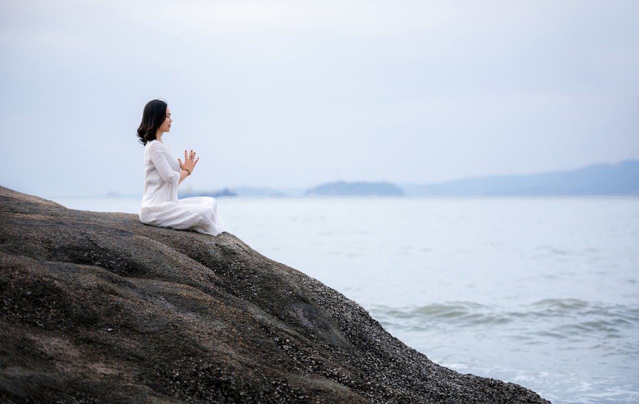 Woman practicing mindfulness meditation by the sea to manage anxiety and stress