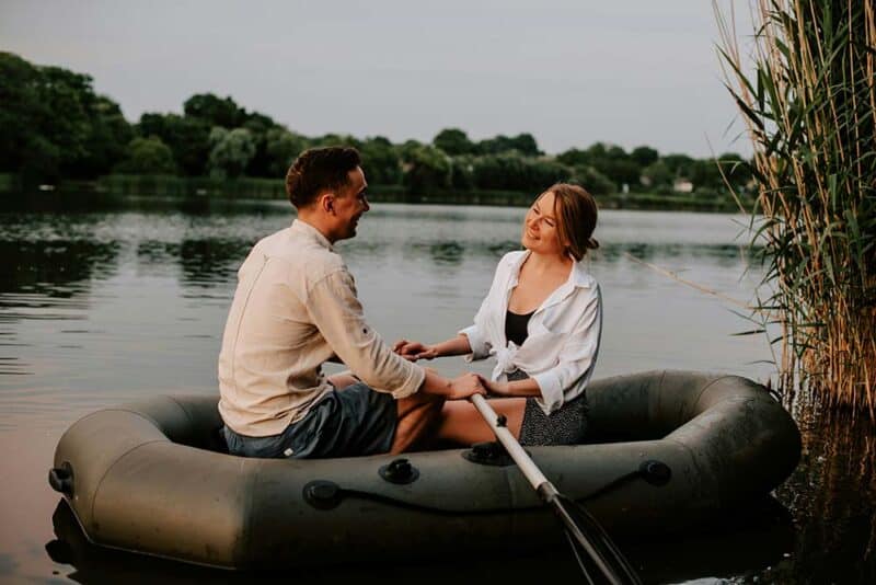 A man and a woman sitting together on a raft on calm water.