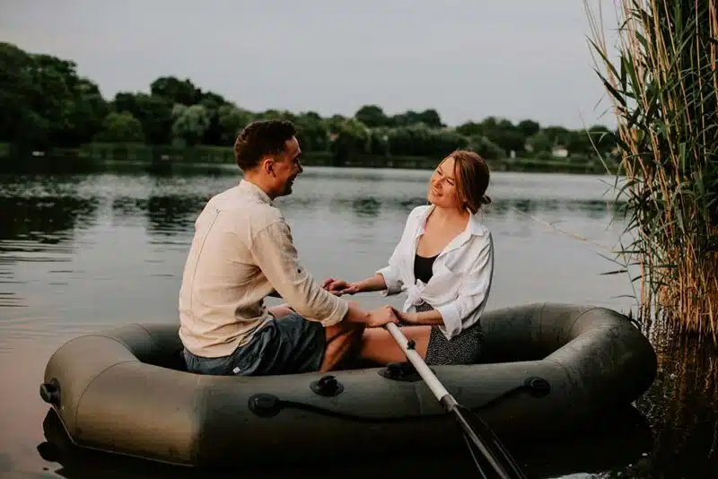 A man and a woman sitting together on a raft on calm water.