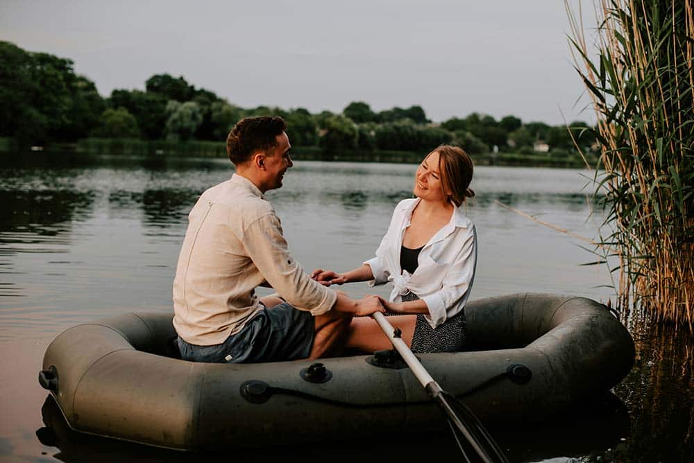 A man and a woman sitting together on a raft on calm water.